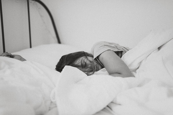 sleeping woman, black and white, white bedding